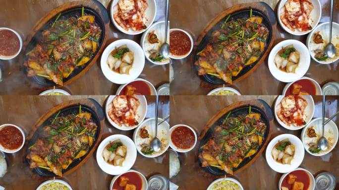 当地韩式美食热盘滋滋滋的猪器官头内脏和皮肤辣酱配菜俯视图慢动作