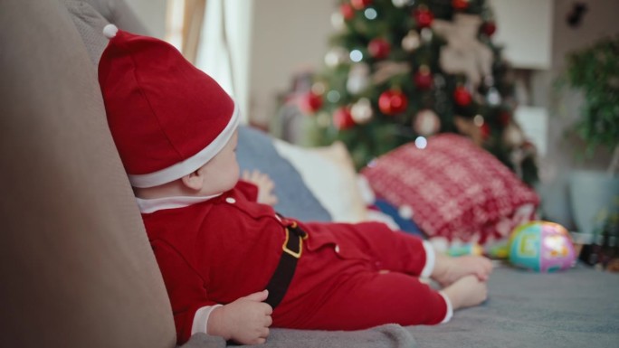 圣诞期间，可爱的小男孩穿着圣诞老人的服装倒在家里的沙发上
