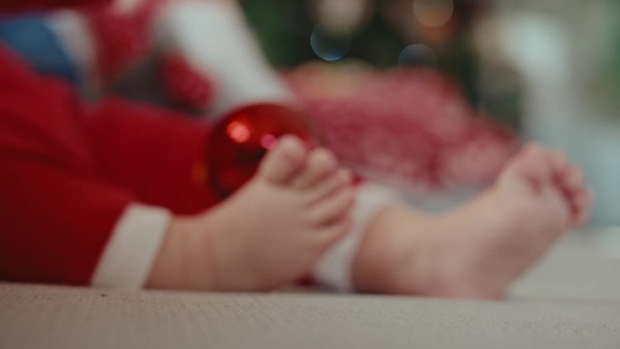 圣诞期间，父亲将闪亮的红色小玩意放在男婴的光脚上