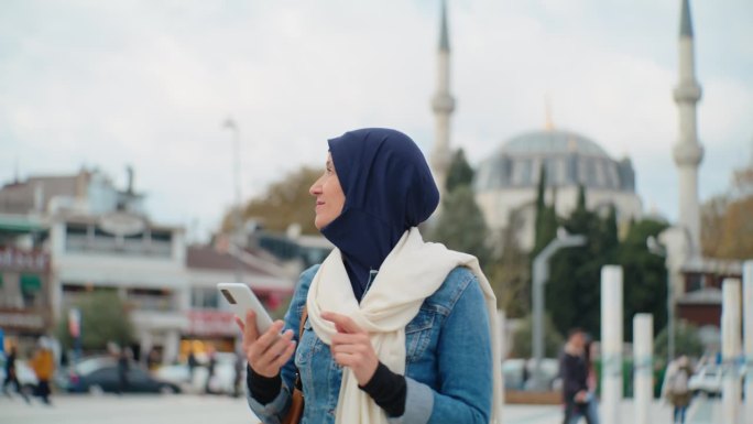 女游客在伊斯坦布尔一座清真寺前行走时使用智能手机#清真寺连接#数字沉思#伊斯兰反思