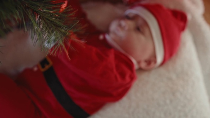 正上方的手持照片，可爱的小男孩在家里玩挂在圣诞树上的小玩意