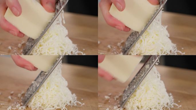 马苏里拉奶酪是用细磨碎器在木桌上磨碎的。特写镜头