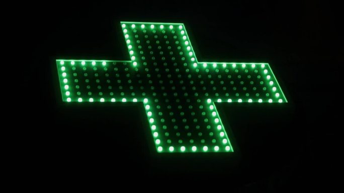 闪电般的大绿色十字标志意味着药店在黑色背景特写