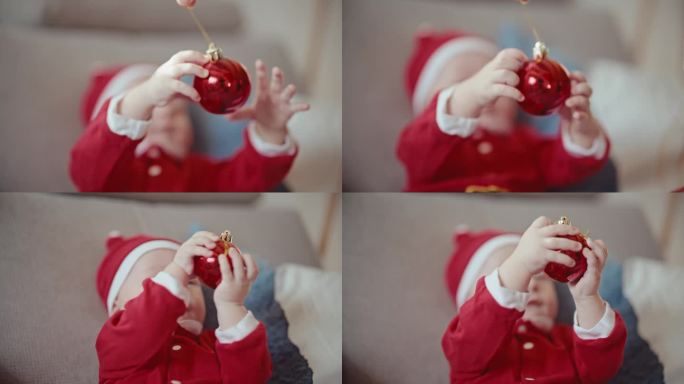穿着圣诞老人服装的顽皮小男孩在家里玩妈妈拿着的红色闪亮小玩意的手持照片