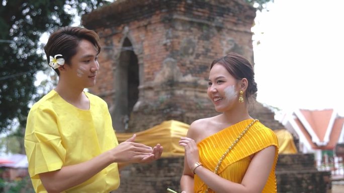 一个年轻男子礼貌地给年轻女子搽粉。在泰国宋干节期间。
