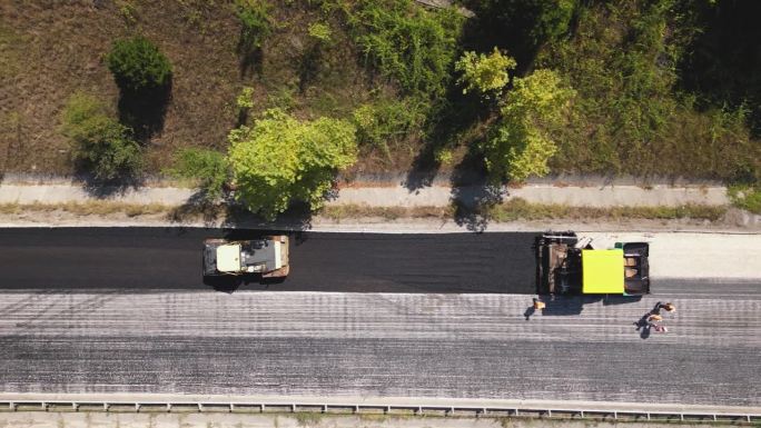 圆柱形滚筒车沥青路面鸟瞰图。双线公路的道路养护工作。