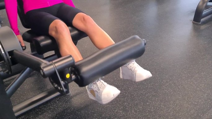 女性腿部在健身房的力量训练机上训练大腿股四头肌