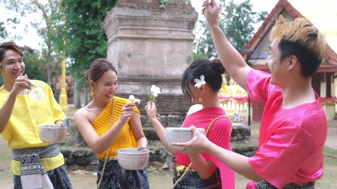 在泰国泼水节期间，一群穿着传统泰国服装的年轻人正在水里玩耍。