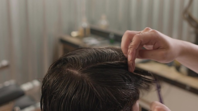 理发师用梳子将顾客的湿发分开