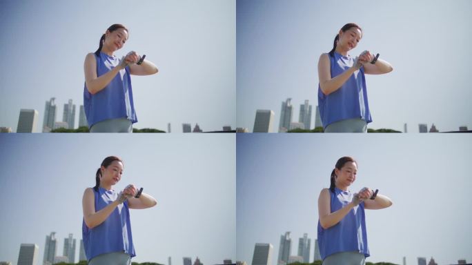 年轻的亚洲女子在城市公园路上慢跑后使用智能手表