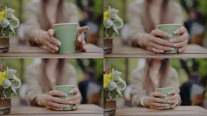 在街边的咖啡馆里，一名年轻女子坐在桌边，用手端着纸杯咖啡