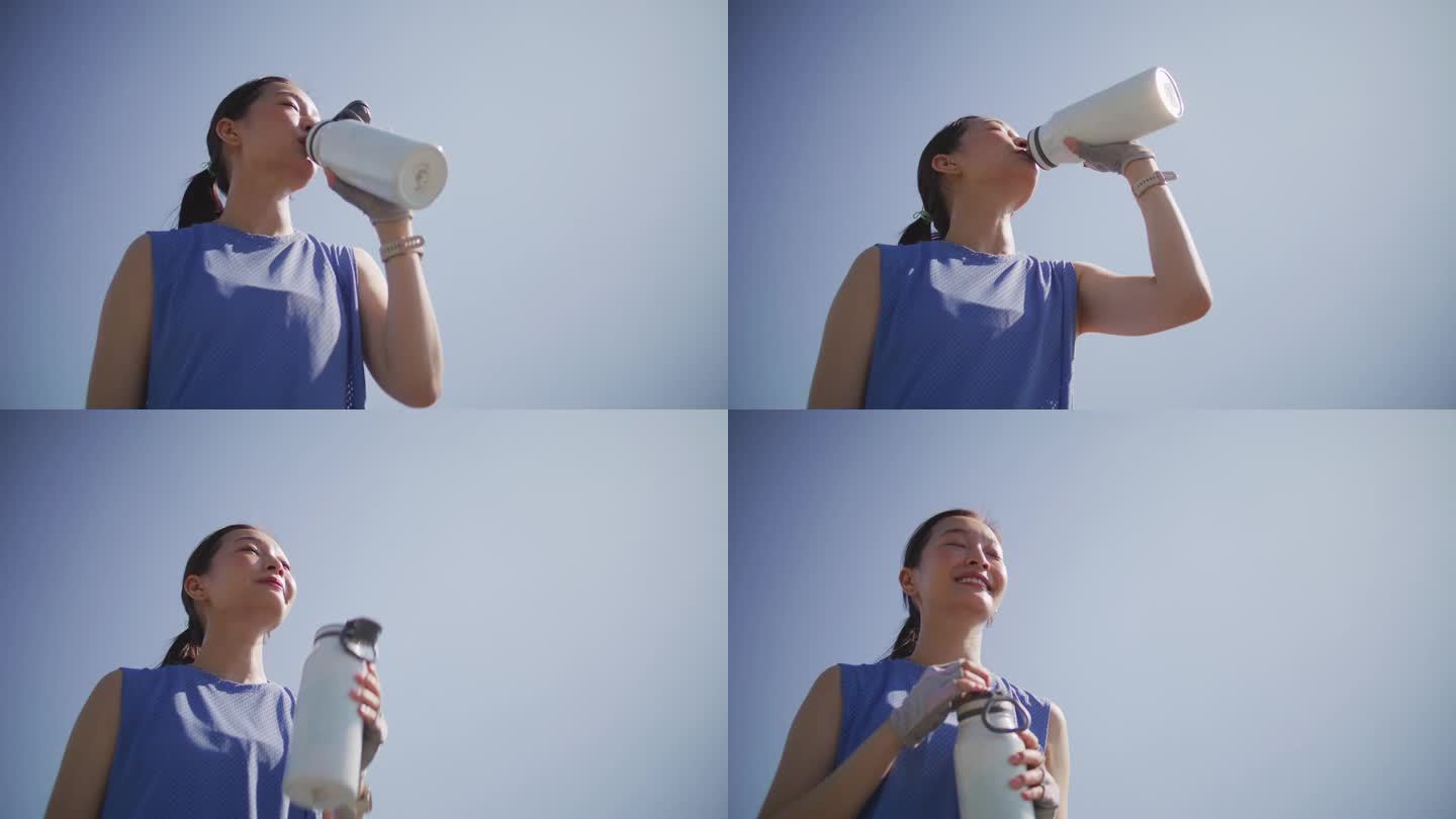 爱运动的女人在阳光明媚的日子里在户外喝水