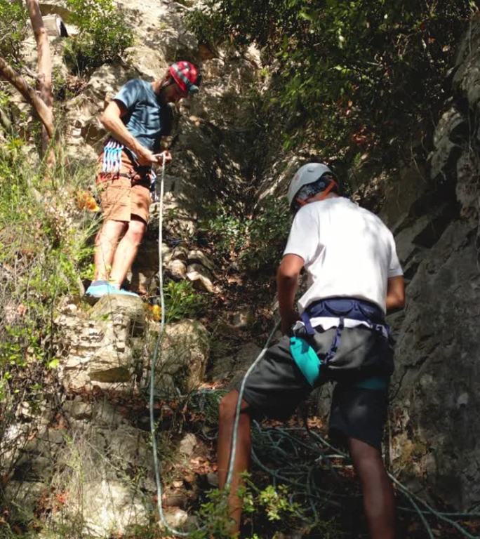 两名攀岩者在一块攀岩岩石前准备攀登安全装备。登山者戴着头盔。