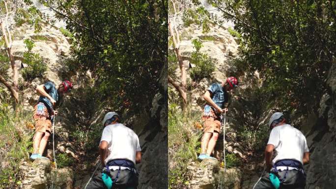 两名攀岩者在一块攀岩岩石前准备攀登安全装备。登山者戴着头盔。