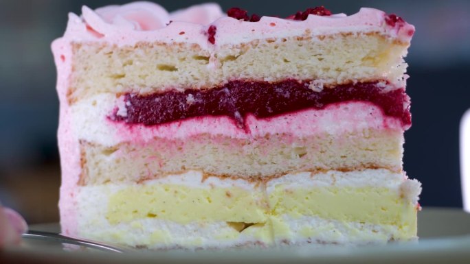 用叉子吃芝士蛋糕。吃一口芝士蛋糕。一个粉红色的草莓蛋糕在白色的盘子里打转。