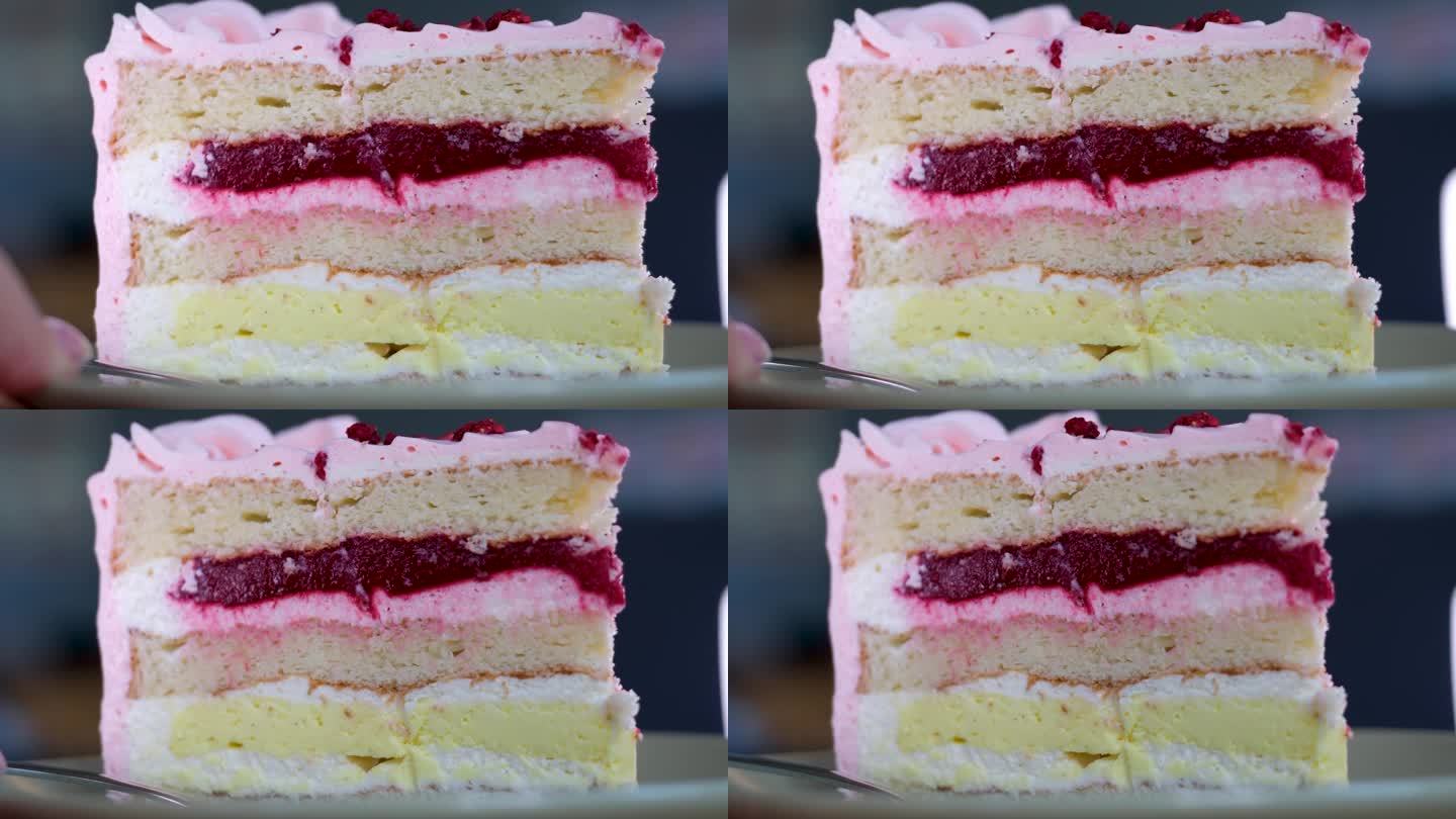 用叉子吃芝士蛋糕。吃一口芝士蛋糕。一个粉红色的草莓蛋糕在白色的盘子里打转。