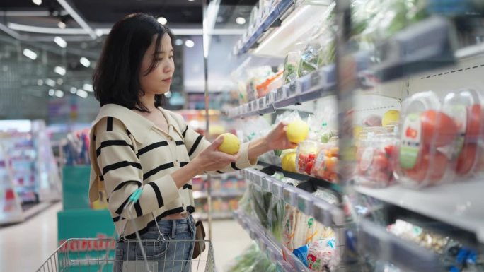身着休闲装的女士在超市挑选新鲜农产品。在百货公司的货架上挑选水果和蔬菜。沉浸在选择食材烹饪营养餐的乐