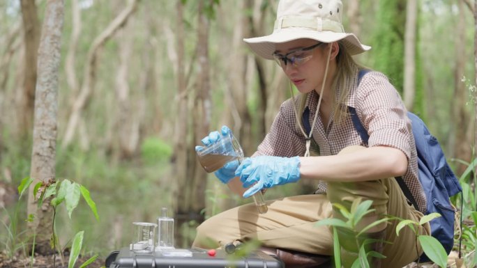 一位年轻的生物学家在泥炭地收集水样，以检查污染物并测量矿物质的丰富程度。