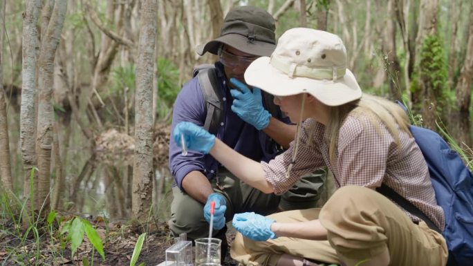 一位年轻的生物学家在泥炭地收集水样，以检查污染物并测量矿物质的丰富程度。