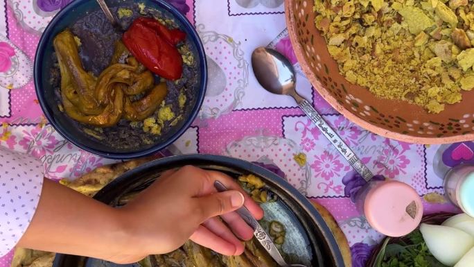 在伊朗呼罗珊农村，在粉红色的台布上品尝传统食物，农村传统的紫色食物，由西红柿、茄子和库拉特制成，喀什