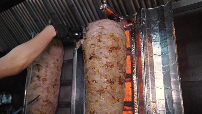 厨师切肉做沙瓦玛，陀螺，烤肉串。把肉串在烤肉串上