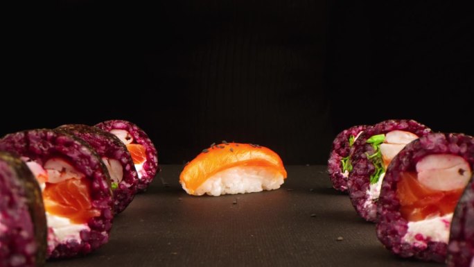 在黑暗的工作室背景下，鲜亮的寿司卷的特写。健康食品的概念，海鲜和新鲜的鱼。寿司菜单，日本料理和亚洲料