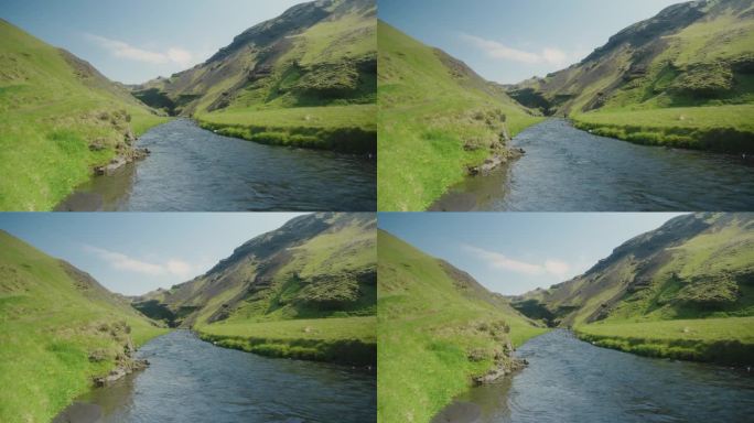 冰岛的一条小河和长满青苔的小山，前景是阳光明媚的绿色岩石和蓝色的水