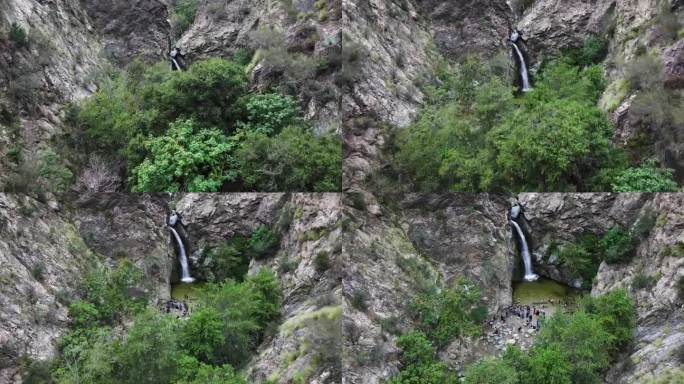 在加利福尼亚州帕萨迪纳的洛杉矶，一群人俯瞰伊顿峡谷瀑布，汹涌的瀑布和郁郁葱葱的绿色植物