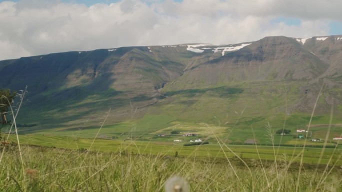 冰岛北部的田野和美丽的雪峰随着时间的推移，云层的阴影在山上滚动