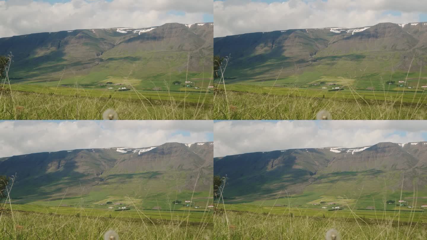 冰岛北部的田野和美丽的雪峰随着时间的推移，云层的阴影在山上滚动