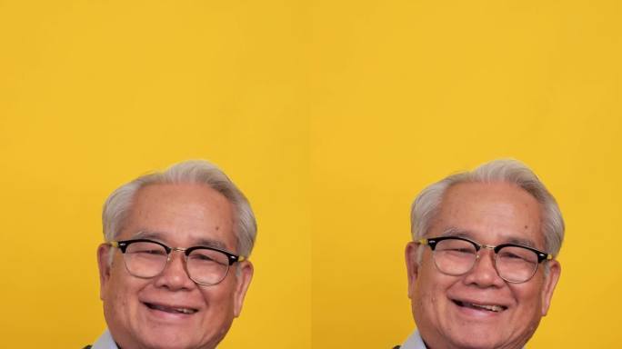 垂直夹。一位亚洲老人用手做了一个心形。孤立在工作室的黄色背景上。