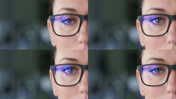 女性绿眼的超级特写正面镜头:戴着眼镜的美丽白人黑发女子在模糊的背景下看着相机。概念:视力、验光师和医