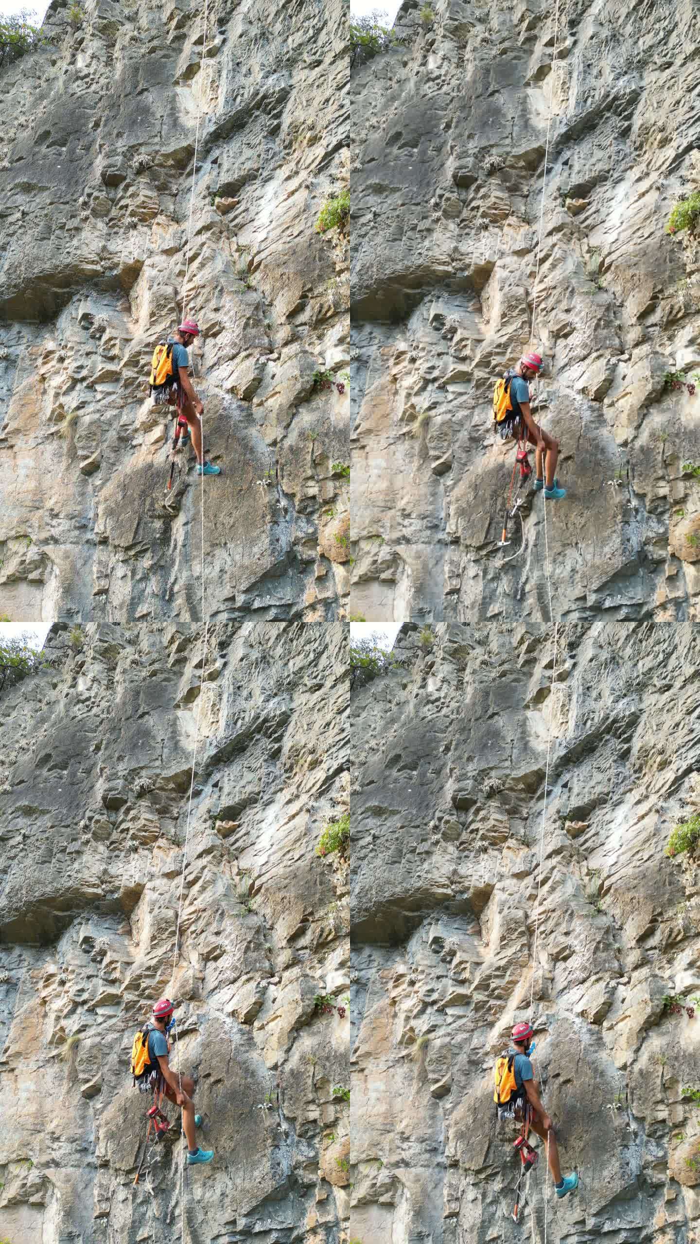 攀爬者用凿岩机和旋锤在攀爬绳上开辟一条新的攀爬路线后，用绳子往下走。登山者戴着红色的头盔。