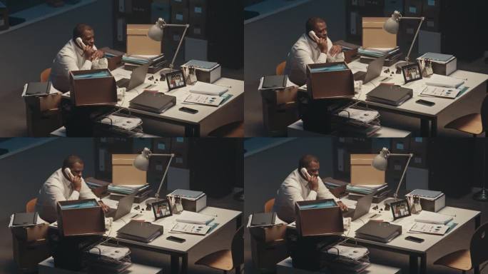 黑人男性主管在夜间办公室用固定电话讲话