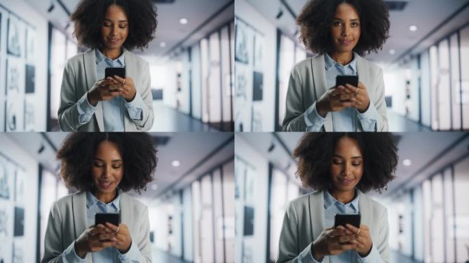 一个微笑的年轻黑人女性在她的智能手机上浏览互联网和社交网络。年轻的女经理查看约会软件，网上购物，给朋