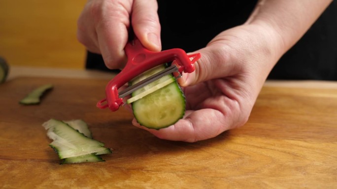 烹饪用的新鲜黄瓜用特制的刀切成小块。做黄瓜菜。缓慢的运动。