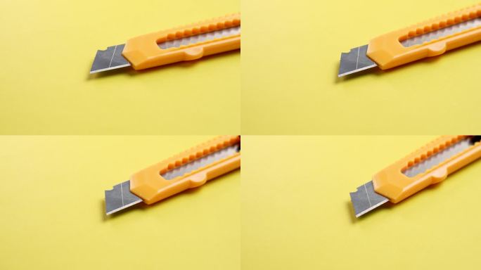 在创造性的黄色背景上有一个可伸缩的分段刀片的美工刀。办公切割工具。旋转