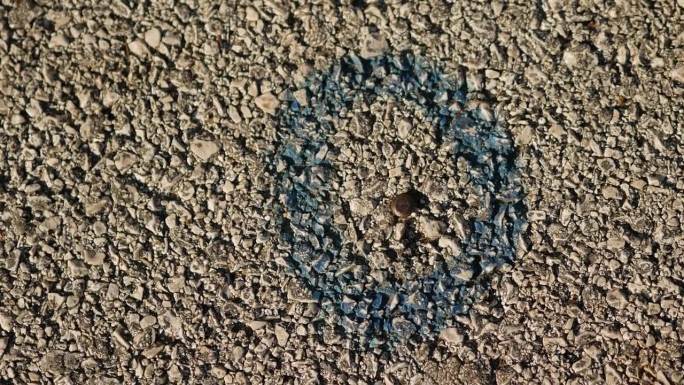 沥青上的大地测量标记。在路上的钢钉周围涂上蓝色油漆的圆圈。纹理背景的字幕。副本的空间。2024年1月