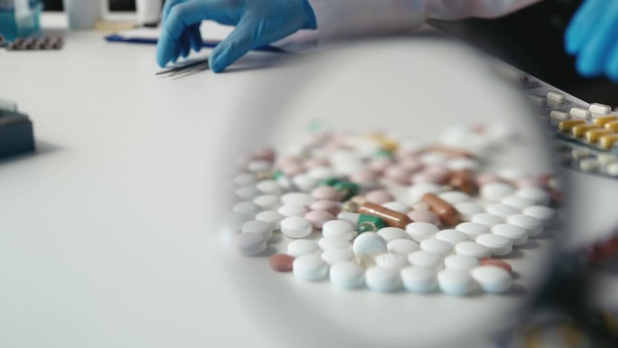 实验室研究人员用镊子拿着药片，把质量差的样品收起来