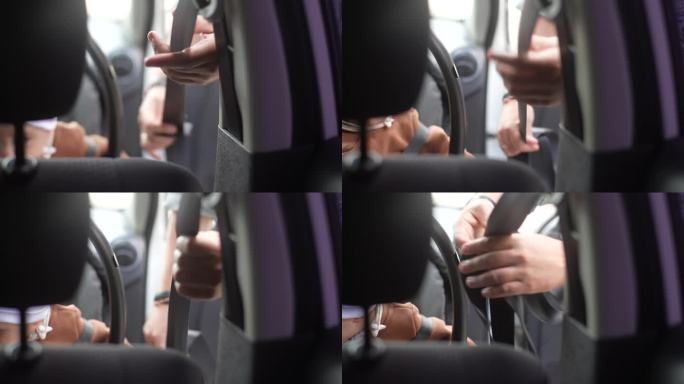 从后座看，无法辨认的妇女正在系安全带的婴儿男婴坐在前座背对发动机。车内系着安全带的可爱孩子。