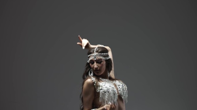 一个女人穿着漂亮的东方舞蹈服装跳舞。性感的肚皮舞与艺术表现力的动作，一个女孩。舞蹈形象的概念，明亮的