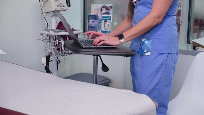 女护士将病人的数据输入笔记本电脑