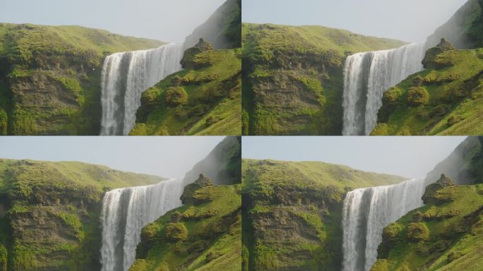 冰岛斯科加弗斯瀑布的中景，美丽的阳光明媚的一天，鸟儿在长满青苔的悬崖和岩石上飞翔，水倾泻而下