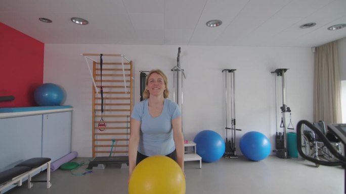 一名妇女正在使用巨型medball或fitball进行康复训练