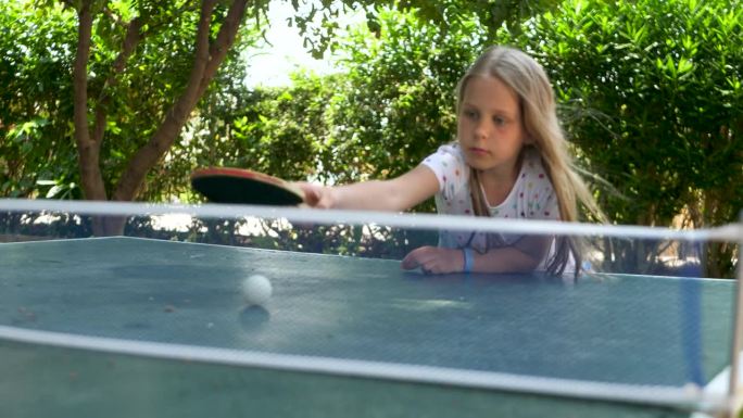 漂亮的情感女孩打乒乓球在绿色的背景