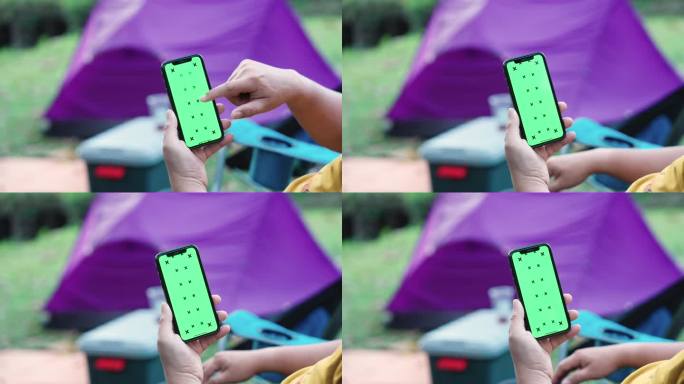 一名男子拿着智能手机，在绿色屏幕的人像模式下，在露营区的帐篷旁边