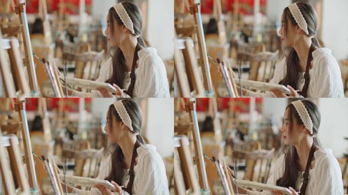 年轻的亚洲女艺术家在艺术工作室画日落风景画。