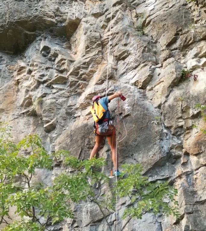 男攀登者用凿岩机和旋锤在攀绳上开辟了一条新的攀登路线。登山者戴着红色的头盔。