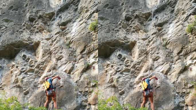 男攀登者用凿岩机和旋锤在攀绳上开辟了一条新的攀登路线。登山者戴着红色的头盔。