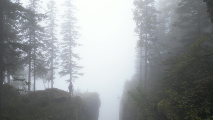 在一个雾蒙蒙、郁郁寡欢的日子里，无人机拍到一个女人走在峡谷边